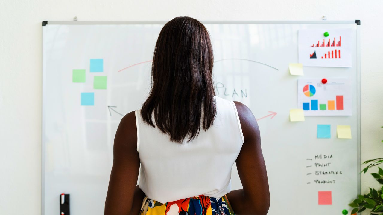 Woman in white shirt studies notes on a whiteboard