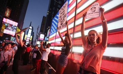 Trayvon Martin supporters stand in front of a lighted American flag in Times Square after marching from a rally for Martin in Union Square on July 14.