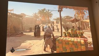 Assassin's Creed Mirage playing from a BenQ X3100i projector onto a white wall