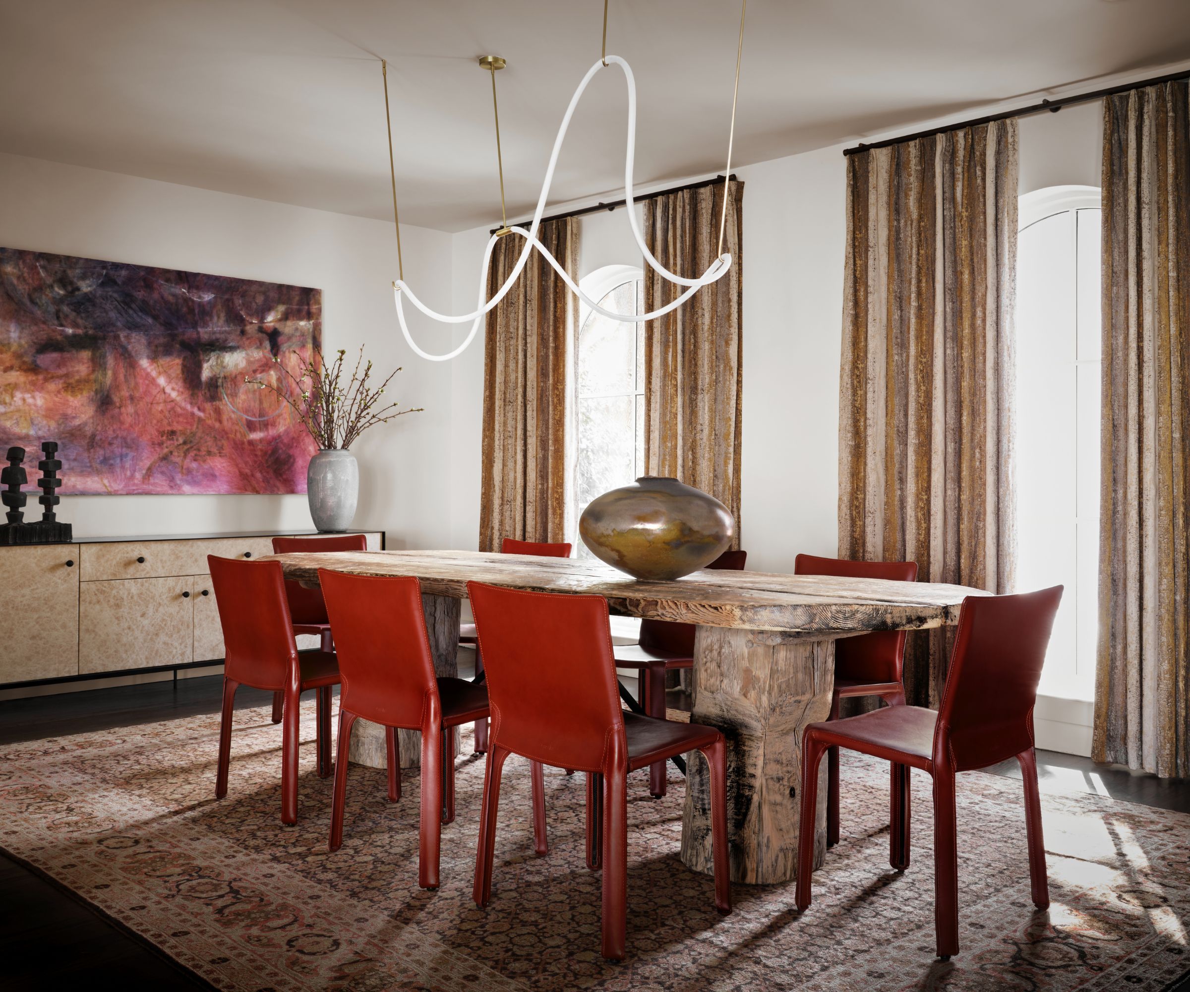 Dining room with abstract modern light, marble dining table, red chairs, abstract art and wood console