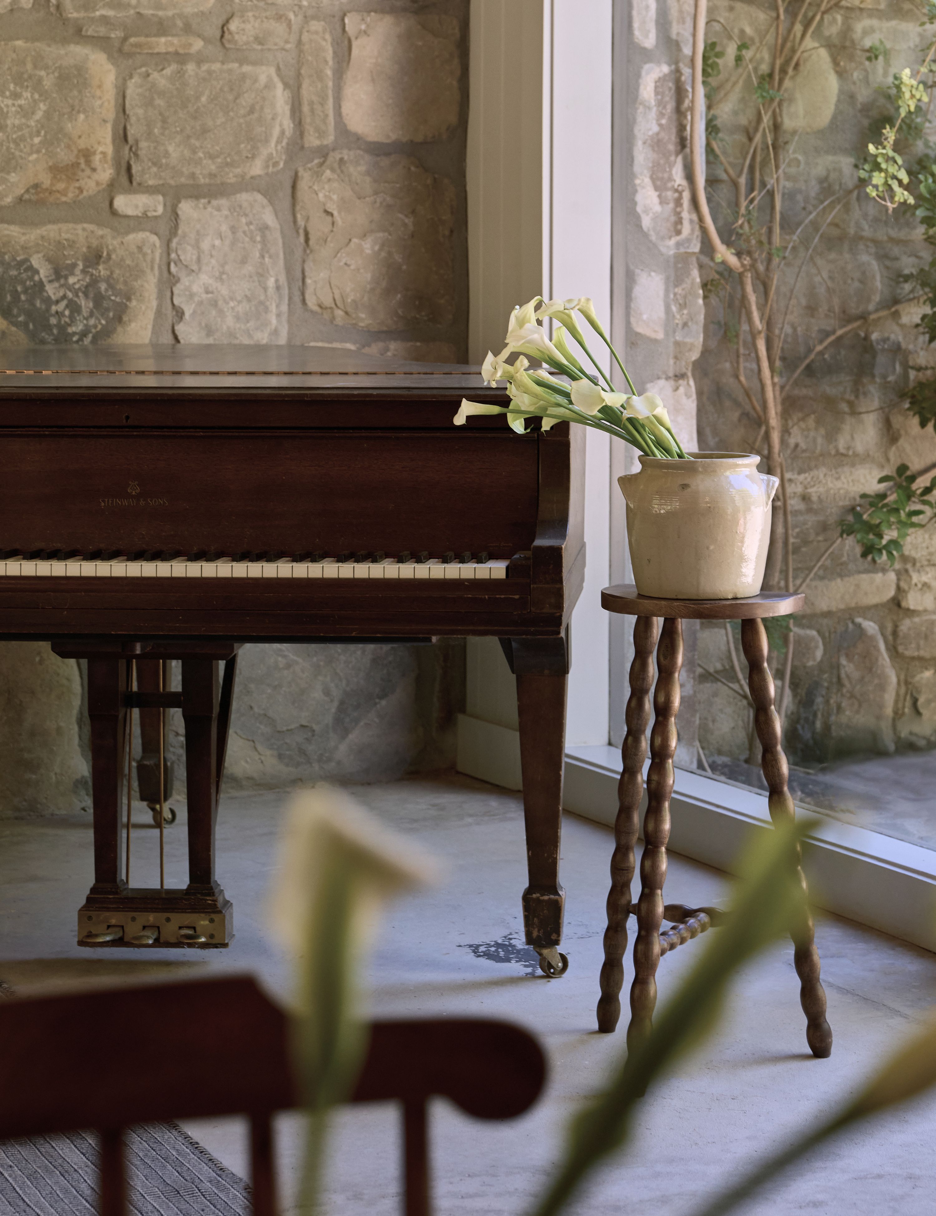 Antique-inspired spindle stool propping up a potted plant, which is styled alongside a piano
