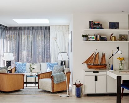 Living room with pale wooden flooring, white walls and soft furnishings with pale grey curtains