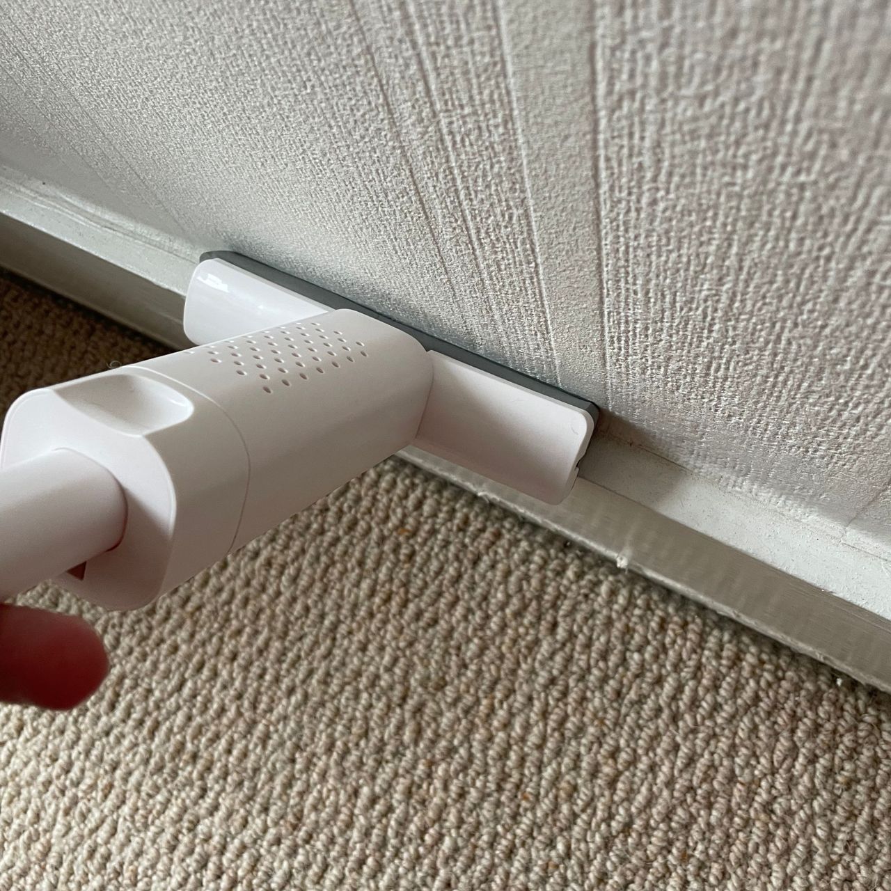 Using a mini mop to dust skirting boards above cream carpet