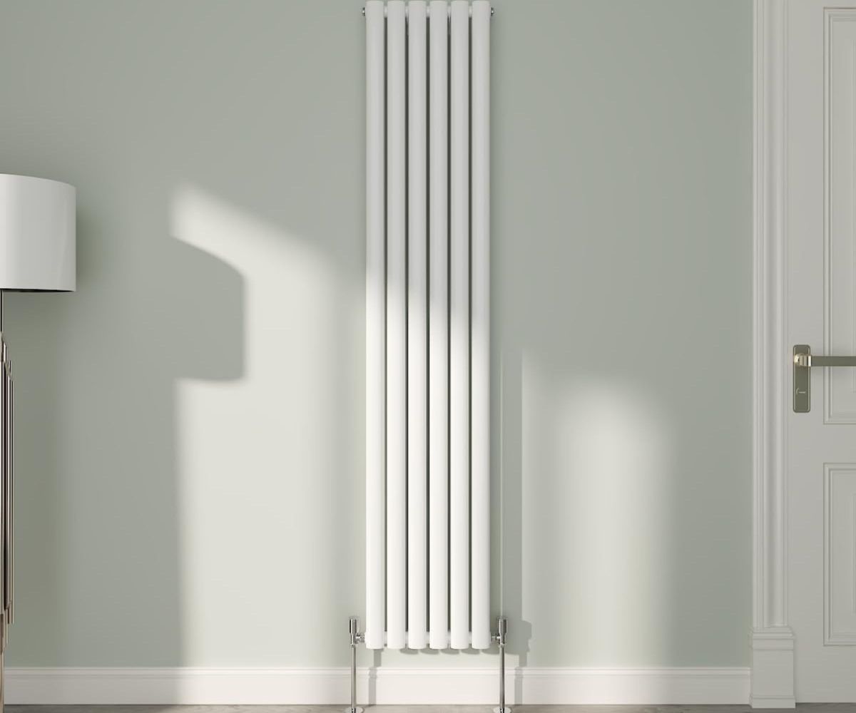 NRG White Oval Radiator Vertical on a green wall next to internal door