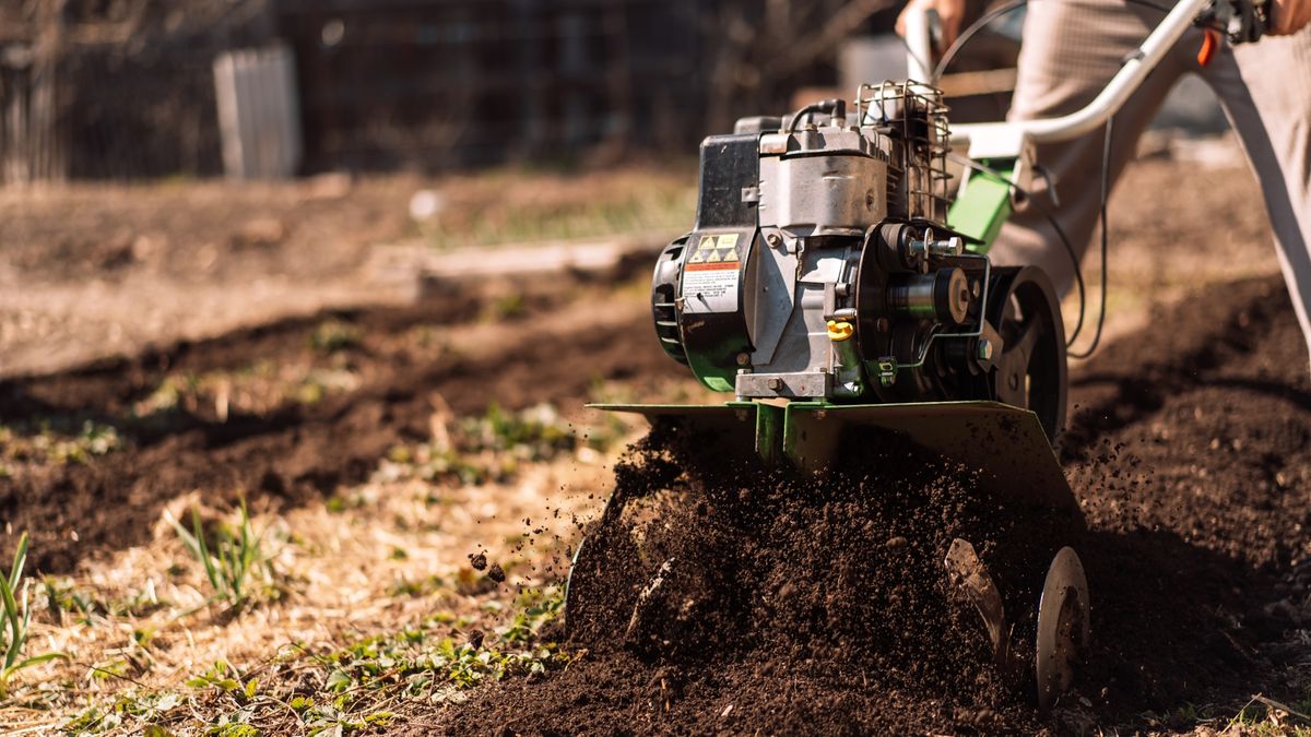 Close up photo of gardener cultivate ground soil rototiller, prepare for planting crop.