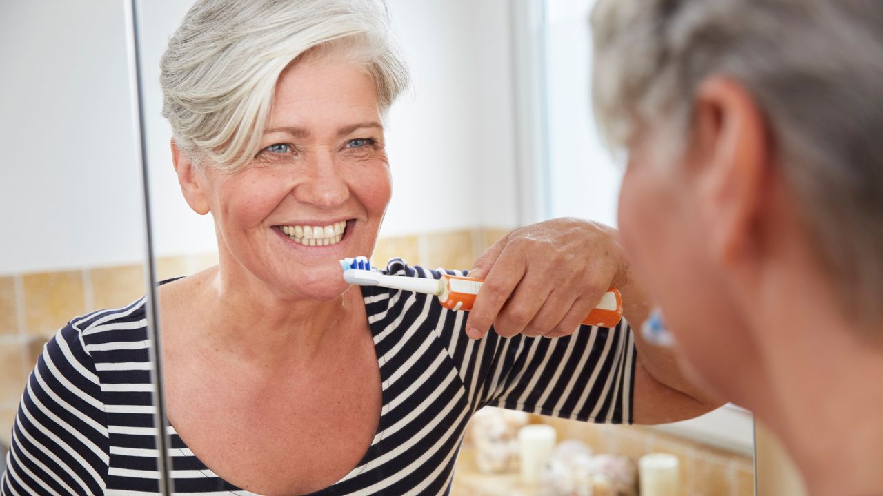 Woman brushing her teeth with electric toothbrush