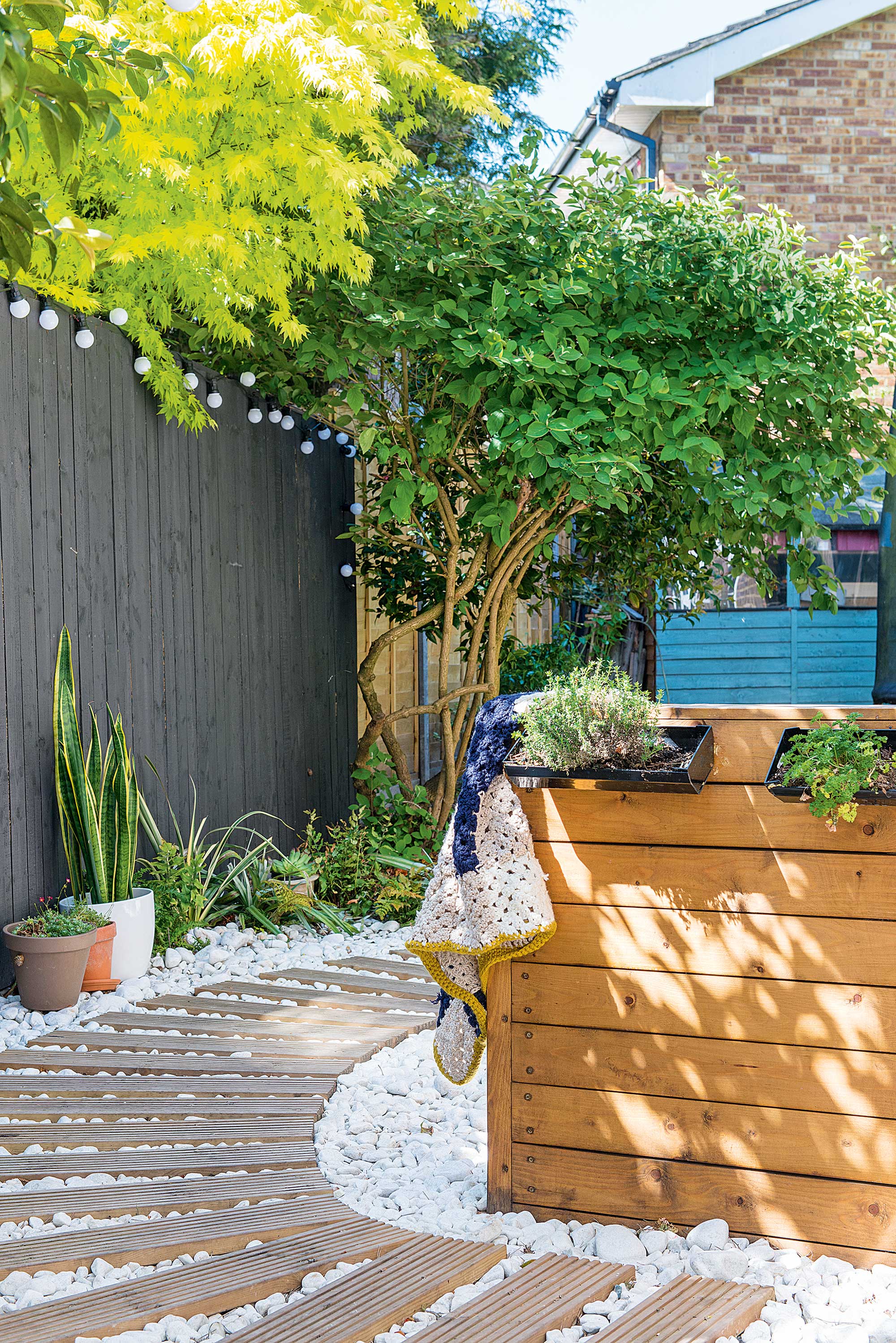 grey fence with festoon lights and curved path