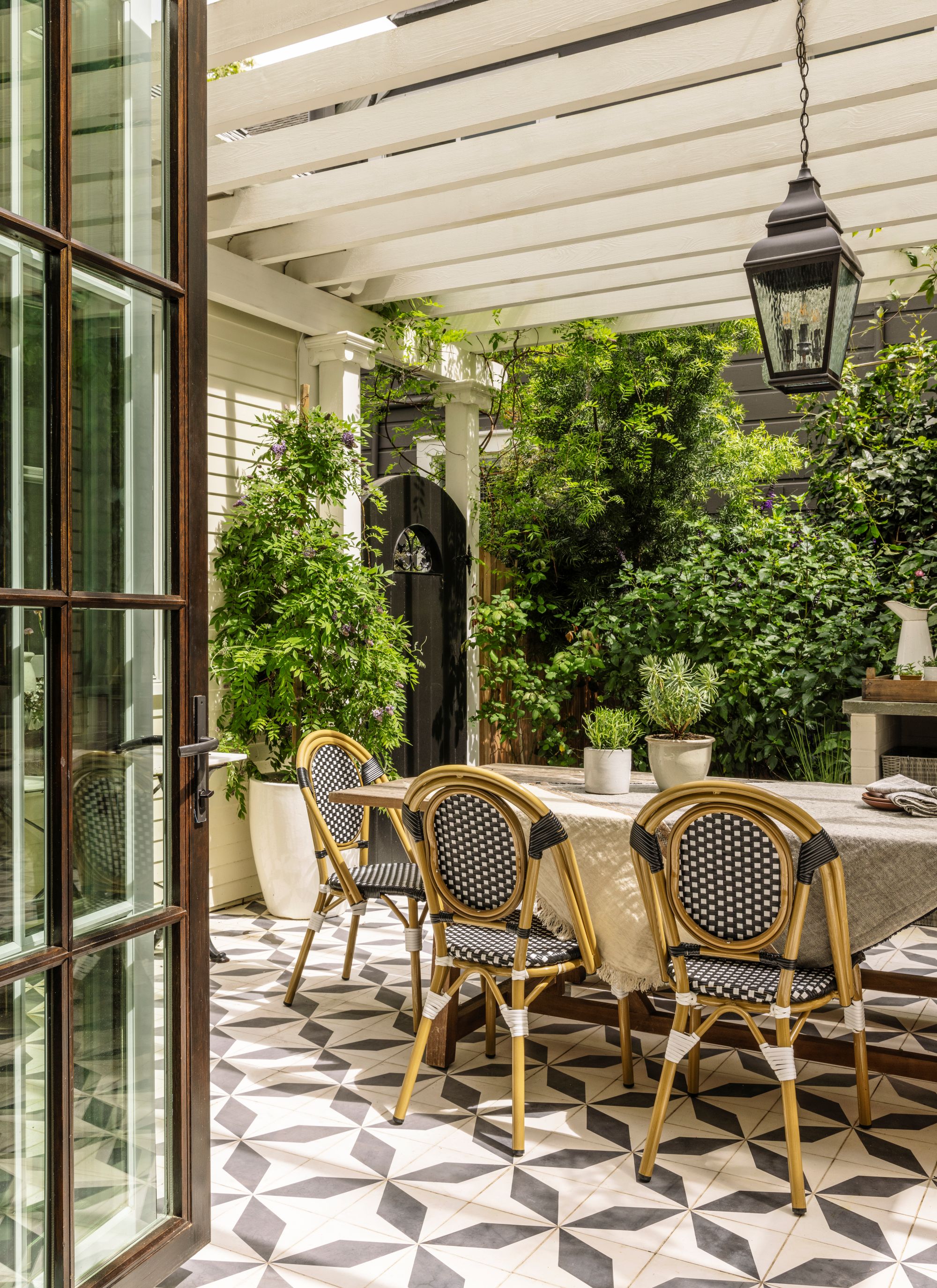 bistro-style outdoor dining area with tiled floors, bistro seating and a pergola structure