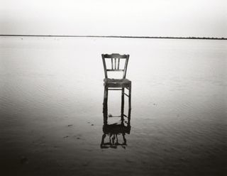 black and white photography of a chair in water
