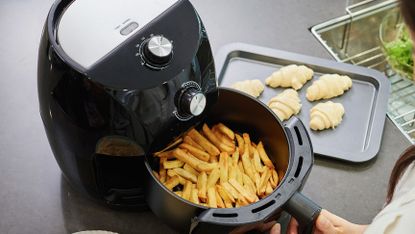 a hand using an air fryer to cook chips