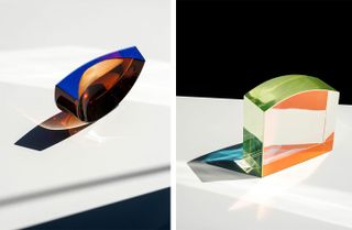 Two glass objects by John Hogan: left, a semi-circular clear sculpture with a blue edge, right, a green-tinted parallelepiped with a curved side