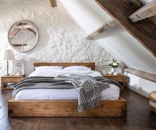 low wooden platform bed in bedroom with sloped walls