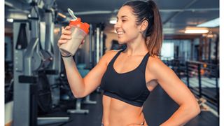 Woman drinking a protein shake post-workout with her hand on her hip