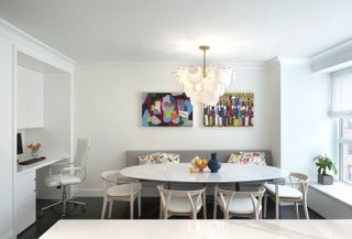 A modern dining room with an oval table, statement lighting , and art work on the walls