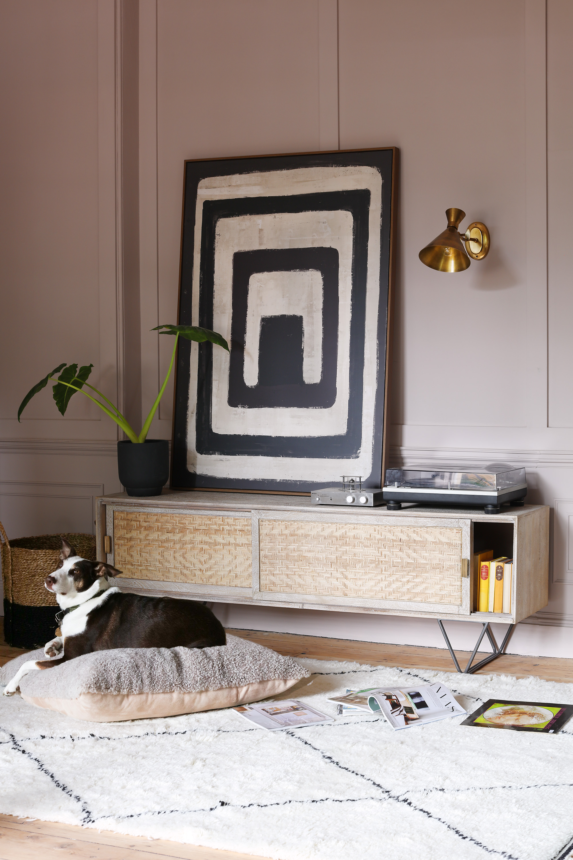 pink living room with large black and white artwork on a side board, metallic wall light above record player