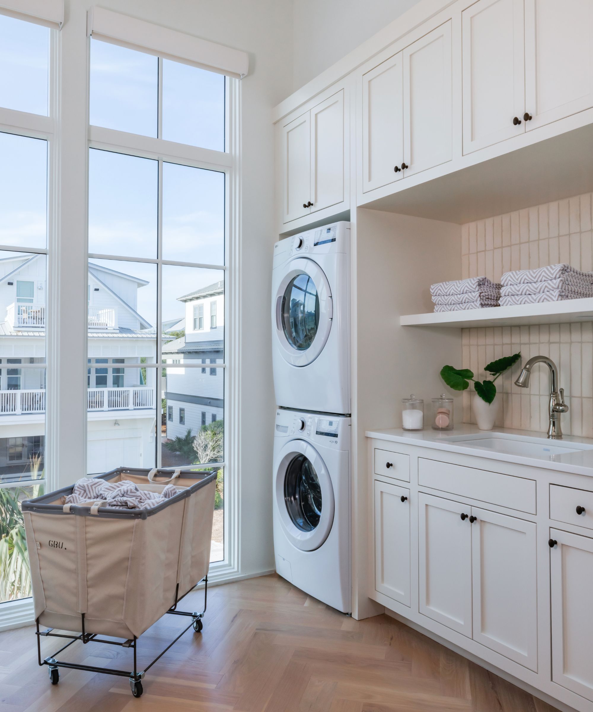 Neutral laundry room with a parquet floor and a stacked washer and dryer