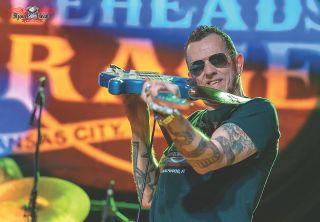 Gary Hoey on stage pointing at the camera with his guitar
