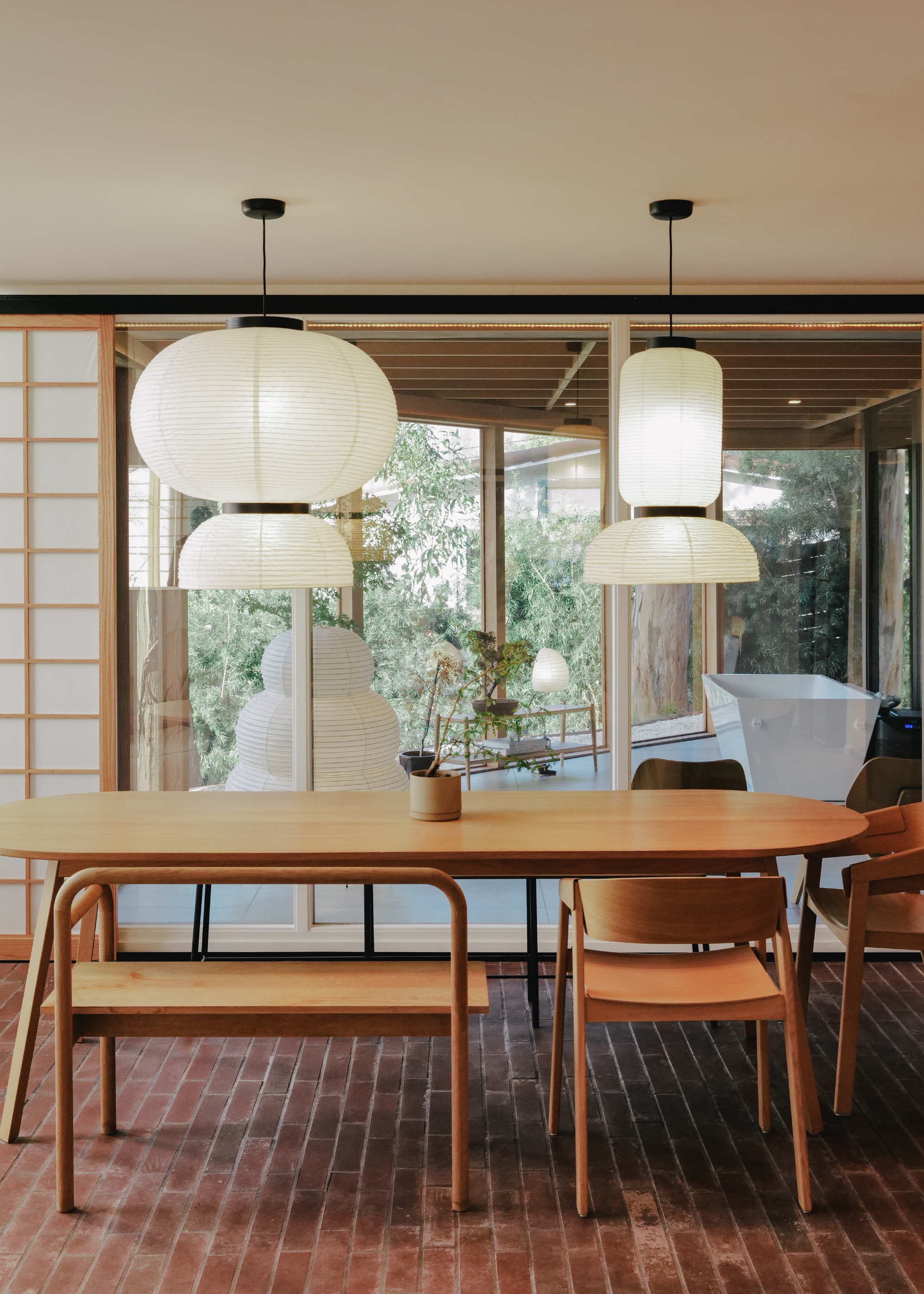 A dining room with paper pendant lights, a wood dining table, and mismatched dining chairs