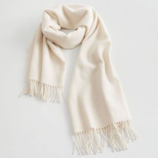 A cream fringed scarf against a grey background