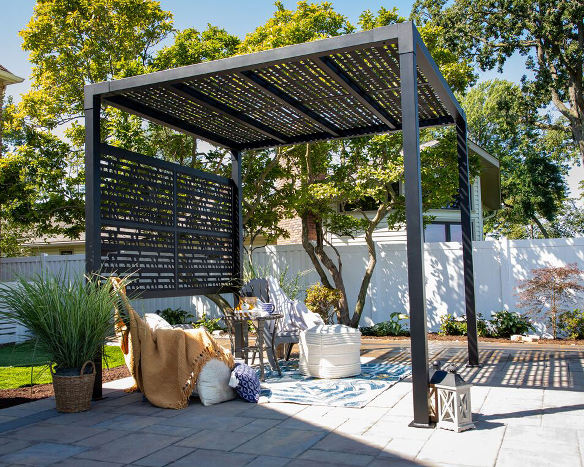 modern louvred pergola deign on patio with garden chair, rug, planters and lantern