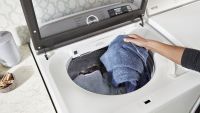 person loading blue towel into the Maytag MVW7232HW top load washer