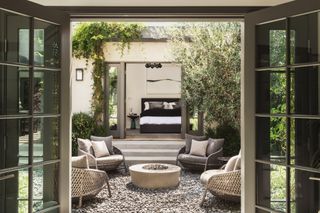 Small courtyard with four grey rattan armchairs arranged around a small firepit