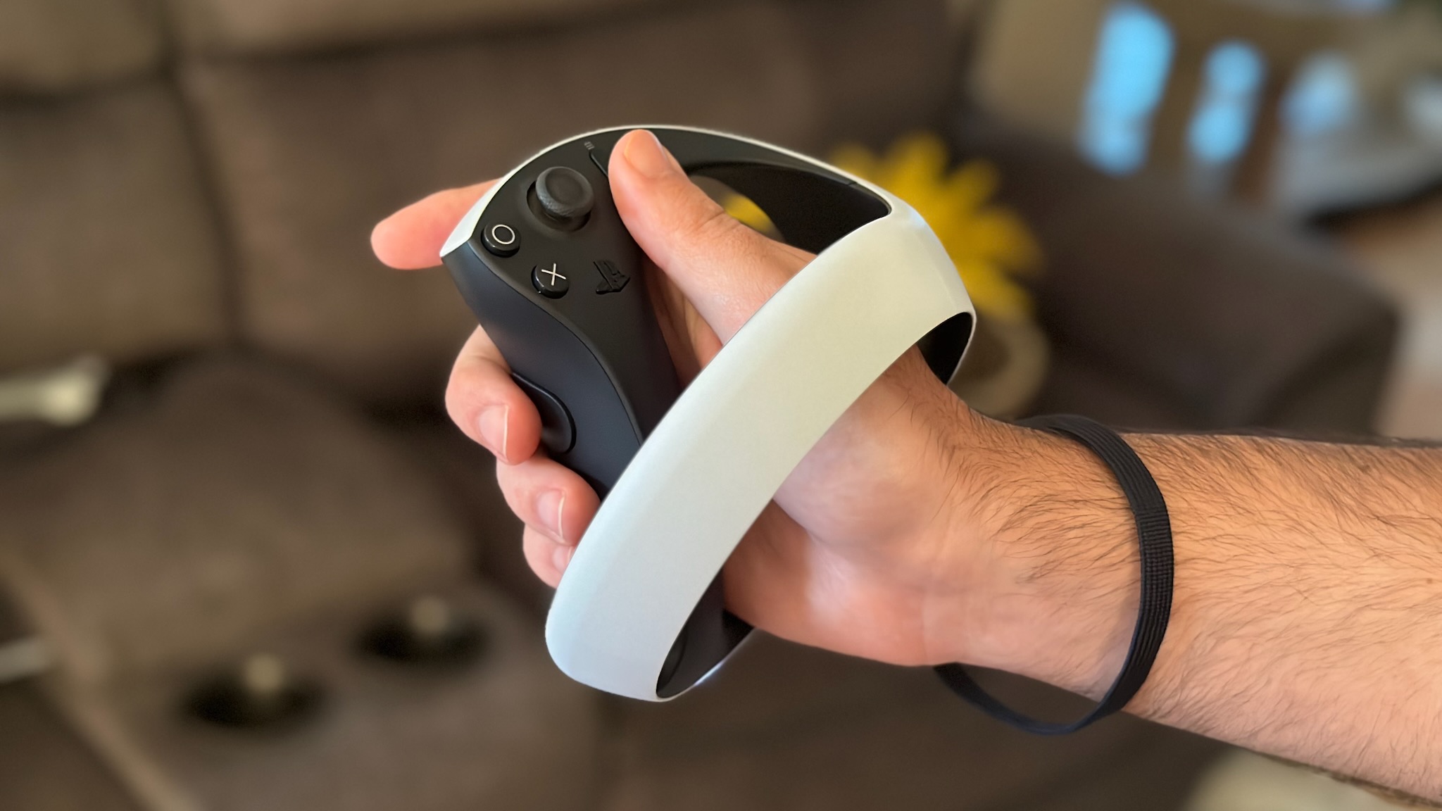Sony PS VR2 Sense controller held in hand with strap attached to wrist.