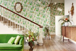 living room with green couch, hallway, stairs, wooden floor, green floral wallpaper