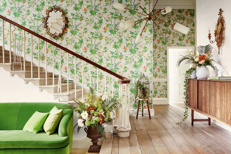 wallpapering tips – living room with green couch, hallway, stairs, wooden floor, green floral wallpaper 