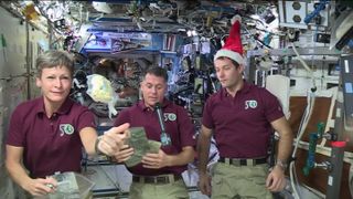 Astronauts aboard the International Space Station show off their Christmas dinner. NASA astronaut Peggy Whitson sends a package of dehydrated mashed potatoes floating in microgravity while holding packets of cider and hot cocoa. NASA astronaut and ISS commander Shane Kimbrough holds packages with turkey, fruit salad, green beans and potatoes. French astronaut Thomas Pesquet looks on in a weightless Santa hat.
