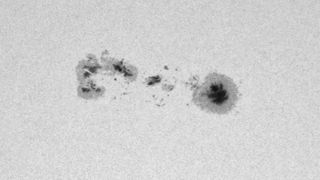 Dark sunspots are visible in a close-up view of the solar surface, which appears white.