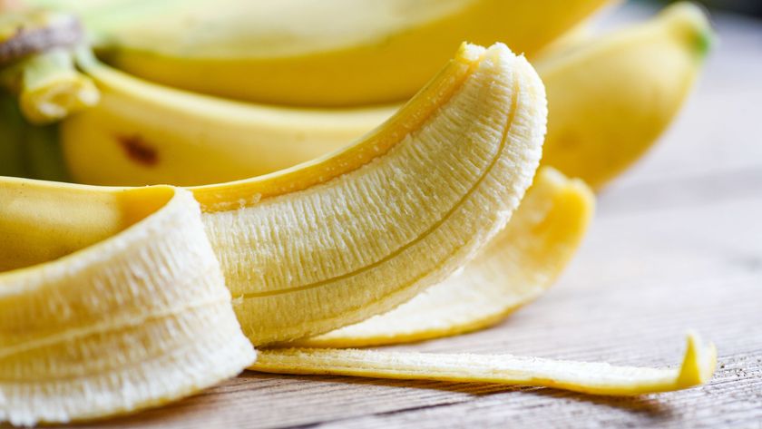 Several bananas with one in foreground peeled