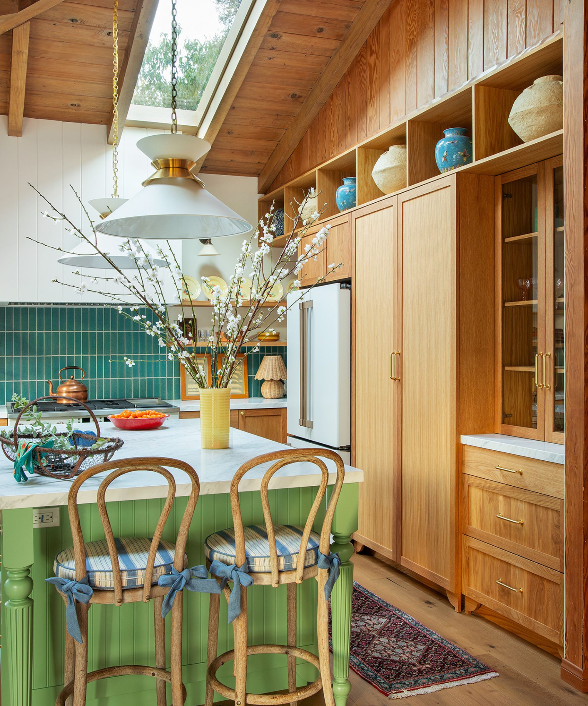 A wooden kitchen with a green island and blue backsplsh tiles