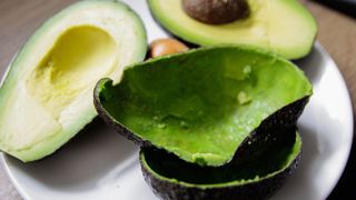 picture of cut open avocados on plate with scooped out skins