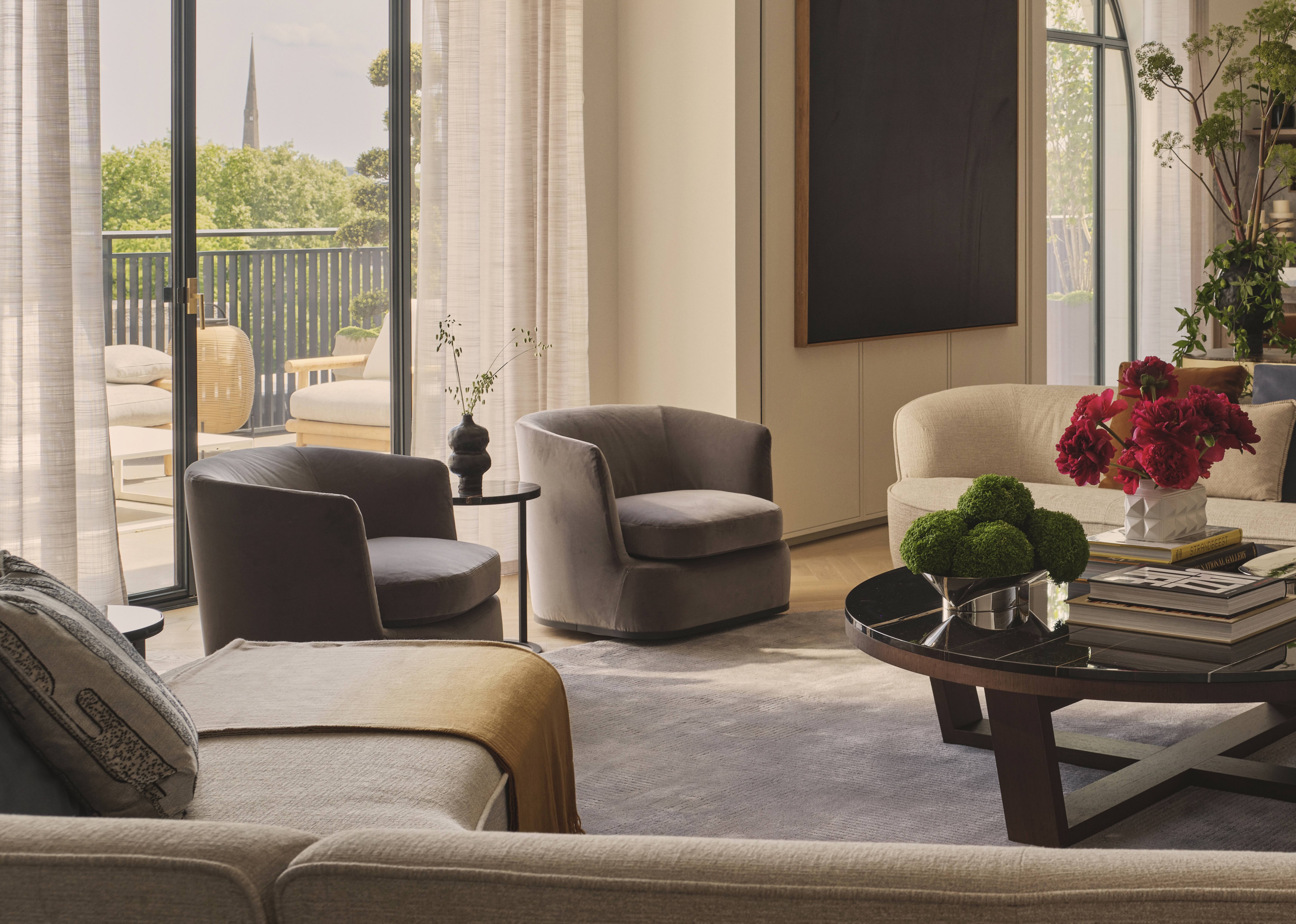 open conversation room with L-shaped sofa and multiple armchairs with floor-to-ceiling windows with large art