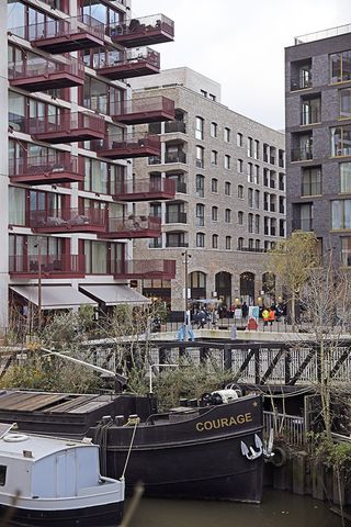 The Brentford Project, showing brick residential blocks with large balconies and warehouse inspired streets and public spaces that step down to the water