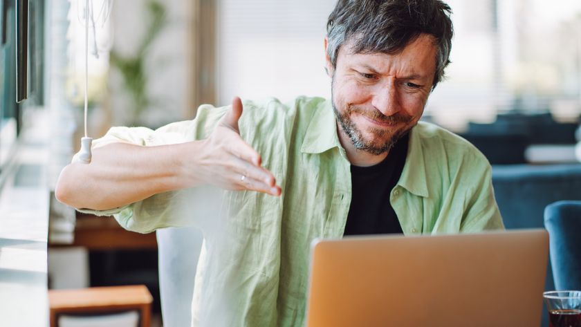 Angry man shrugging and waving hands by the laptop in cafe