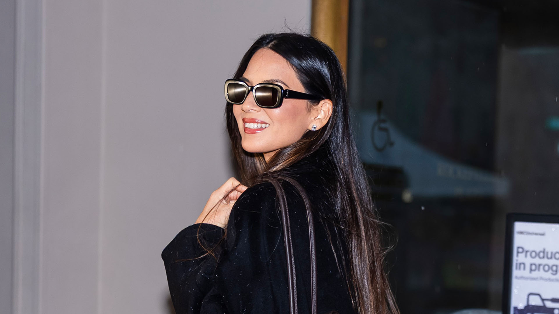 Olivia Munn wearing a black coat, brown bag, and black heels.