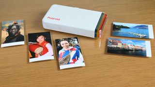 Polaroid Hi-Print portable printer on a desk with sample prints