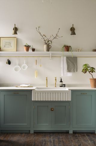 green shaker kitchen with shelving. Fluted sink and brass taps