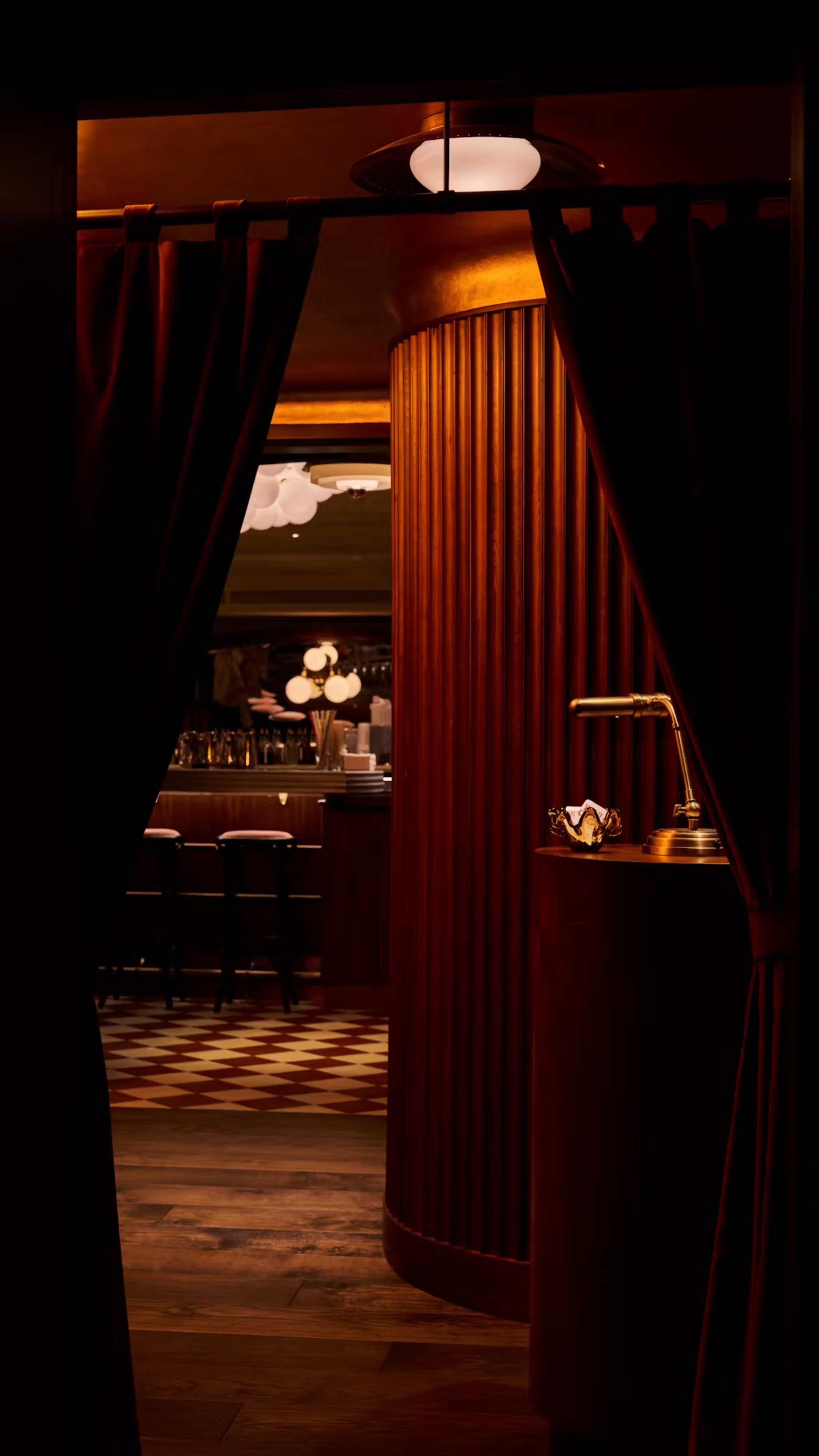 the dramatic, members club style interiors of wild cherry restaurant with a checkerboard floor and green leather seats
