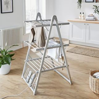 A three tier heated clothes airer in a kitchen with a wooden floor