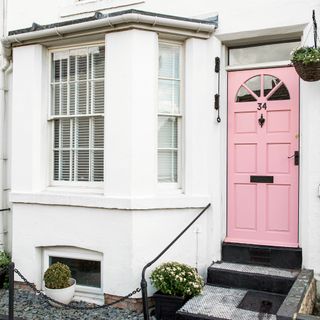 White terrace house exterior with a bay window and pink front door