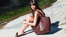 A woman wearing an extra large, deep burgundy YSL tote bag available from ThedoubleF. 