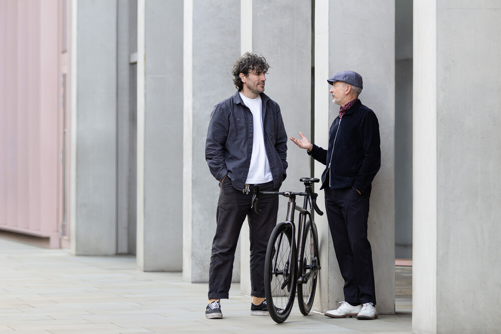 Two men talk with a bike in between them