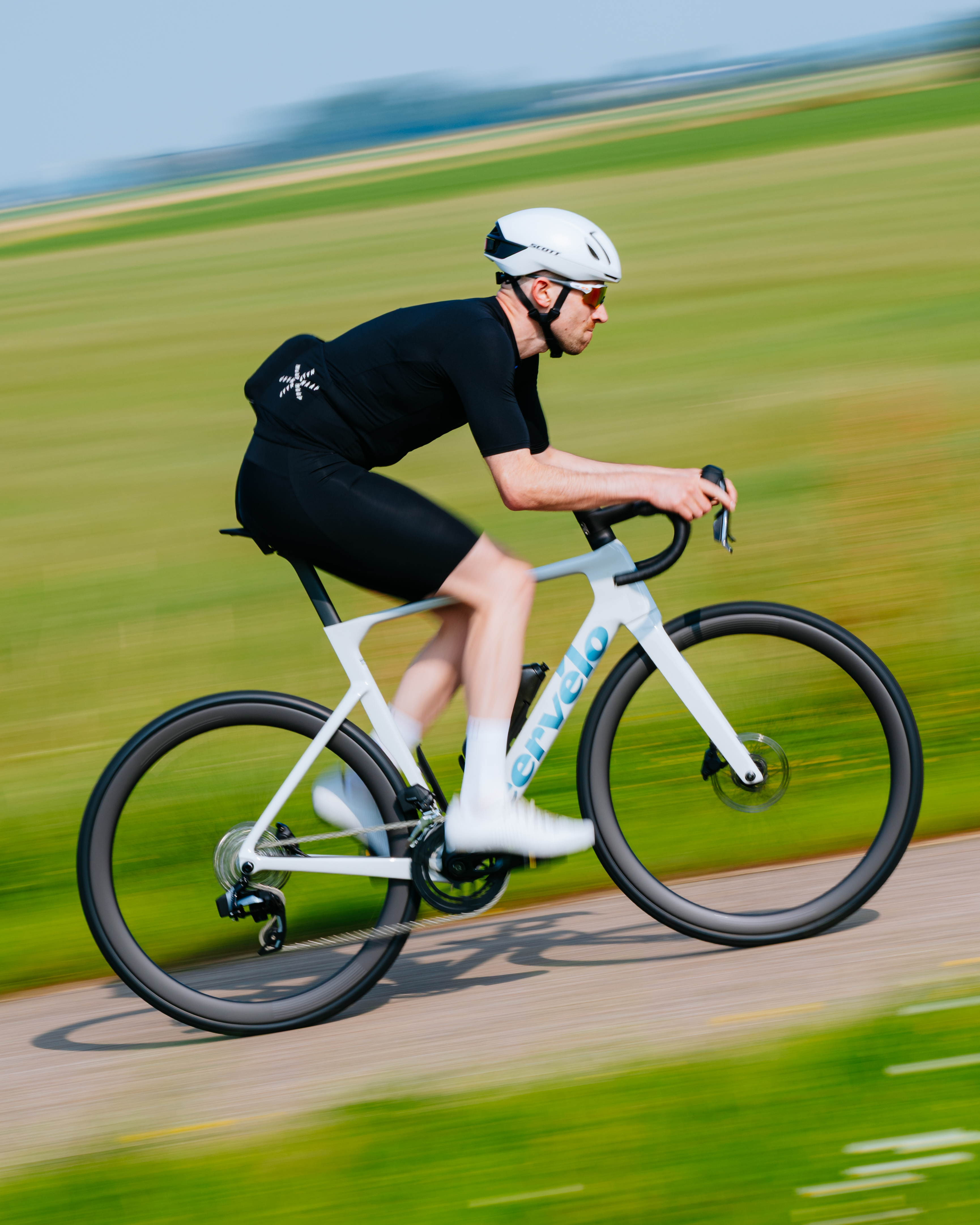 Tom monta um Cervélo Soloist branco em frente a um campo verde.