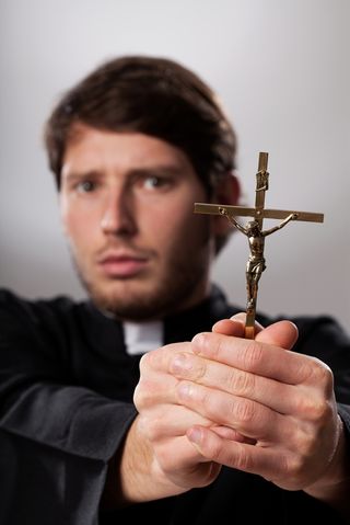An "exorcist" priest holding a crucifix.