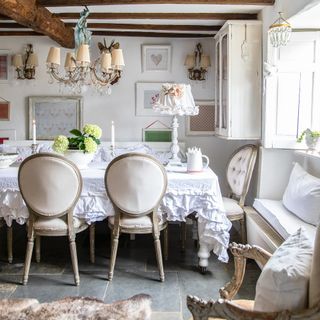 white french country style dining room with pale ruffled tablecloth and lampshade and vintage furniture