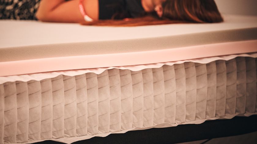 A close-up shot of the coil system inside a mattress while a person lies on the top of the bed
