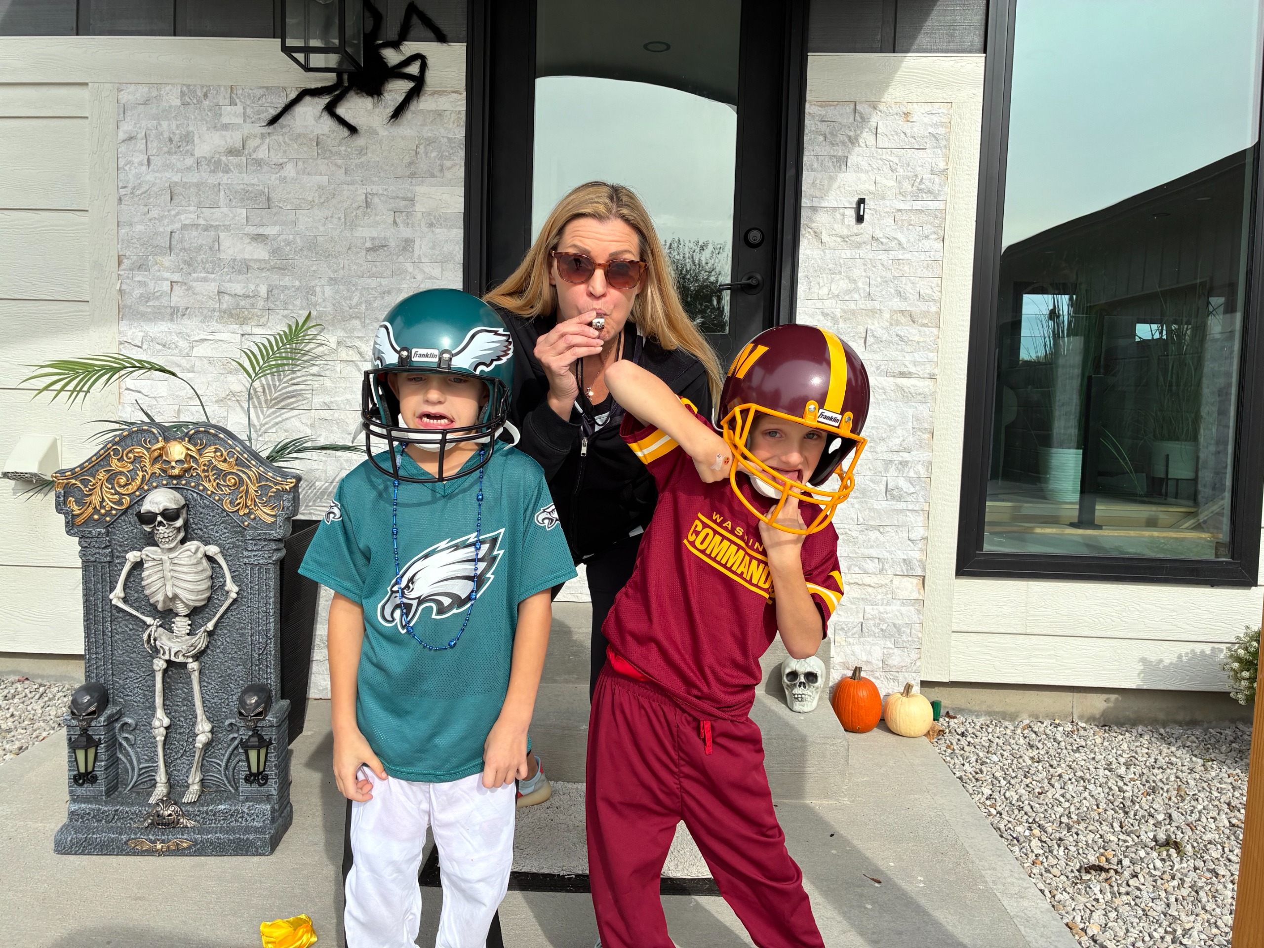 Monica Andreasen stands behind her twin sons, who are dressed in football gear.